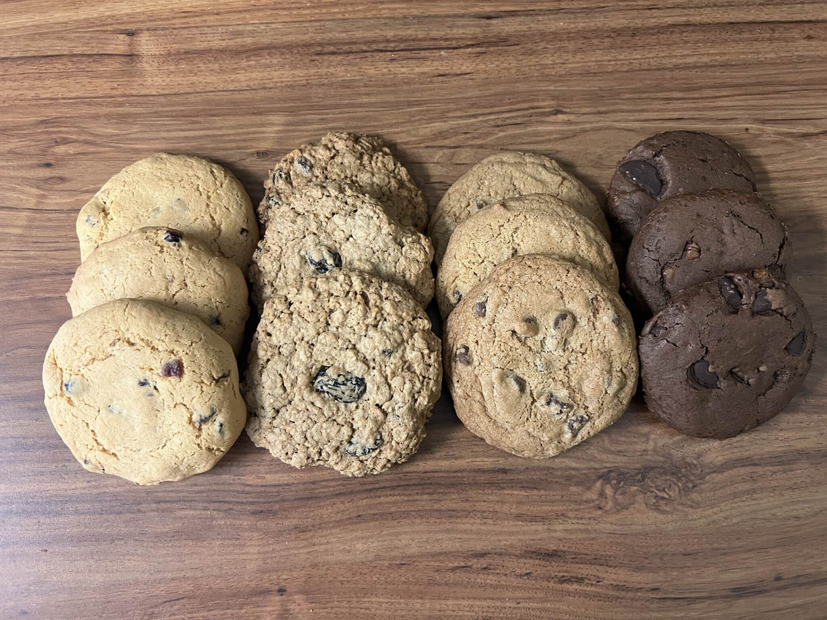 Four flavors of monastery cookies arranged in rows on a wooden table.