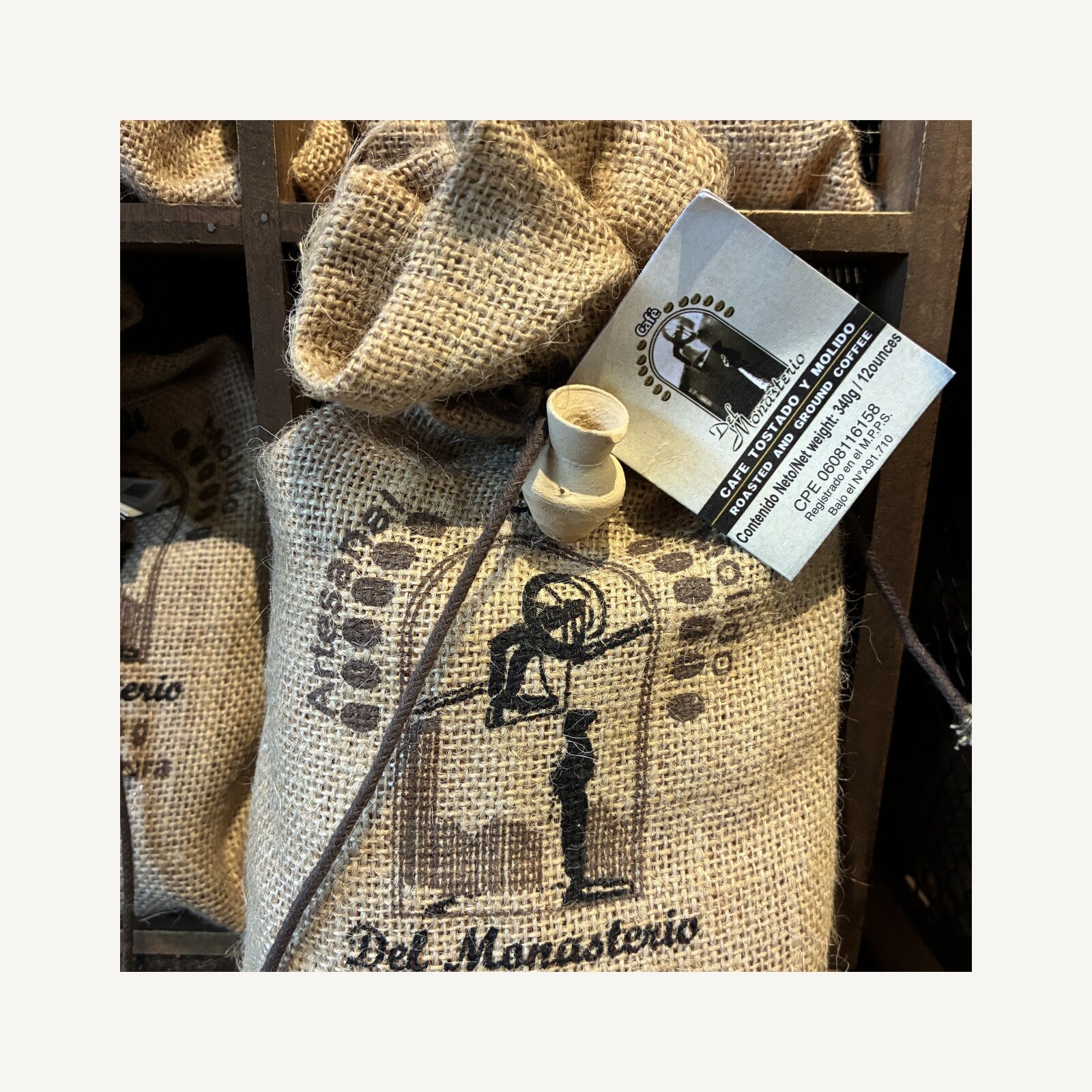 The front of a Cafe del Monasterio coffee sack on the monastery gift shop shelf, showing the monk emblem and the words Arabigo de Altura