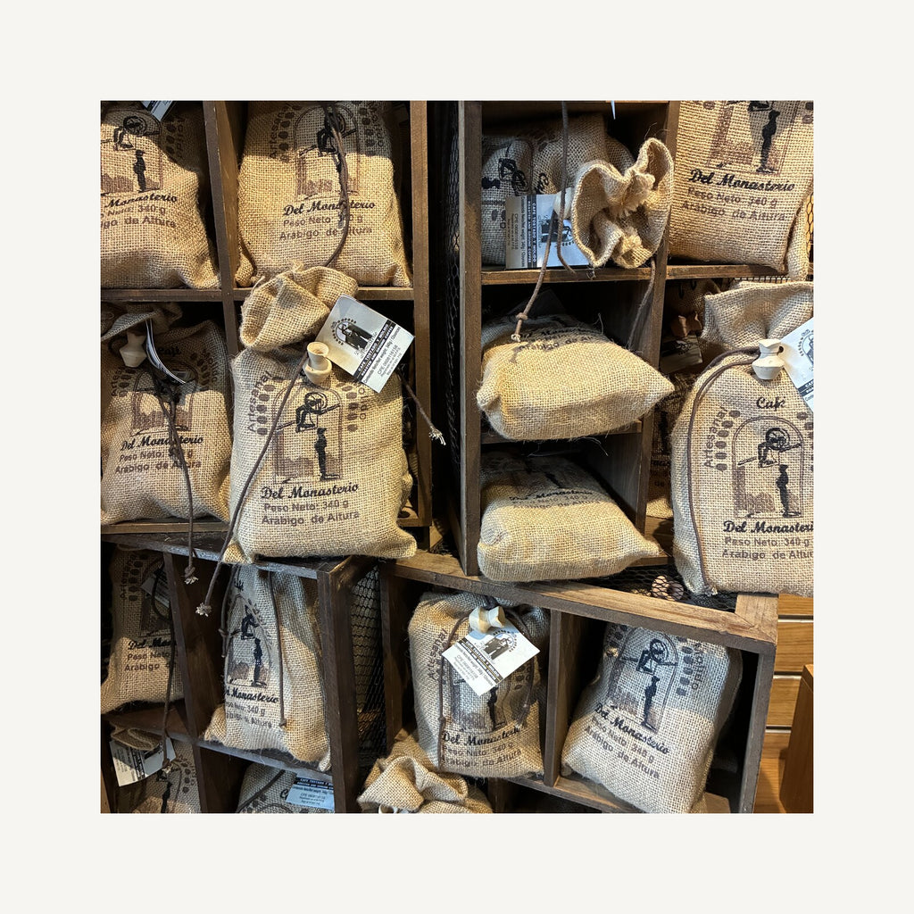Shelves of burlap Cafe del Monasterio coffee sacks stacked in wooden crates in the monastery gift shop
