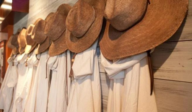 A row of the monks’ straw work hats hanging above their white habits.